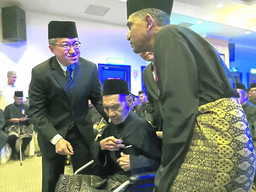 刘镇东（左）颁发马来西亚服务勋章给97岁的选伍军人古兰纳比；后者在英殖民时代已经从军，保家卫国，如今患有严重老人痴呆症，且行动不便，需轮椅代步。