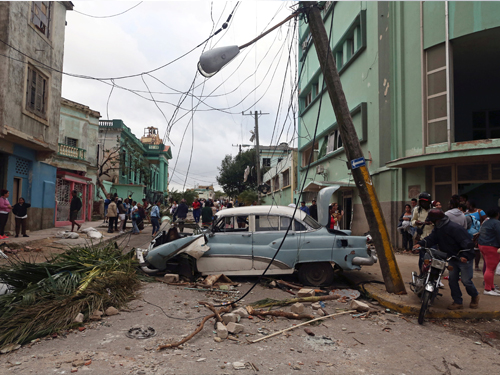 哈瓦那大街的路灯和电线被吹得东歪西倒，车子被建筑物瓦砾砸毁。
