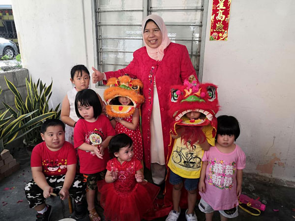 穿着红彤彤衣裳的祖莱达，与新村孩子们及两只小醒狮向国人拜早年。