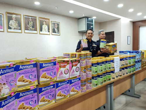莫哈末阿里（左起）与拉斯迪展示警方所起获的各高级品牌奶粉。
