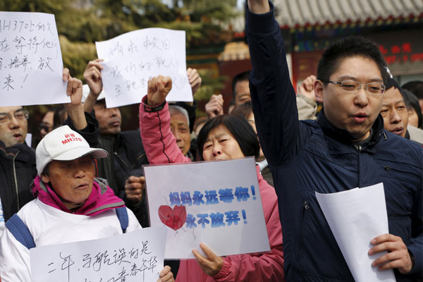 一批乘客家属在北京佛教庙宇雍和宫外,手持“妈妈永远等你,永不放弃!”纸条。
