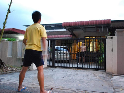 骆建贤（前）和骆建佑（铁门后）几年前回槟城探望家人时，隔着住家的铁门打球，重温儿时乐趣。（受访者提供）