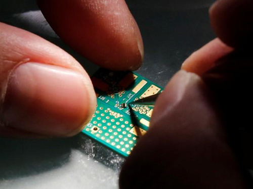 中国目前的芯片组只是在中国设计，但在内地以外的地方制造。图为中国北京一名研究人员将半导体植入接口板上。（路透社）