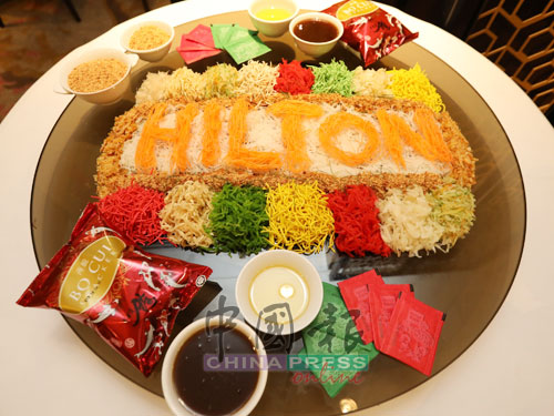 灵市希尔顿酒店烹饪团队特别精心准备了特式双文鱼生（福星高照齐捞生），以红萝卜丝拼出“Hilton”字样，迎接繁荣、健康、美好财富的新一年。