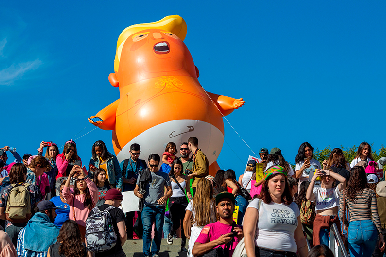 洛杉矶民众在“特朗普宝宝”充气气球前聚集，准备参与游行。（法新社）