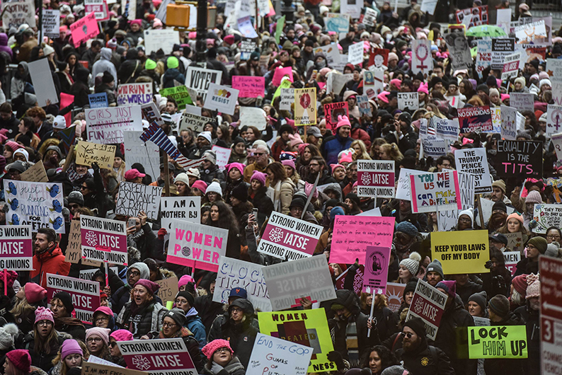 纽约妇女戴着粉红色“小野猫”帽，举起抢眼的粉红标语牌，浩浩荡荡参与游行。（法新社）