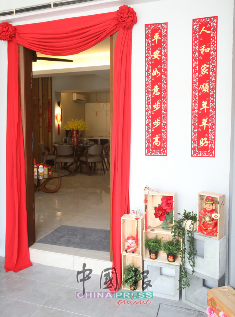 大门处横挂红绣球彩布，贴上象征“家庭安好”的对联，花费不高，却吸引眼球，稍加点缀就烘托出浓郁的节日气氛。