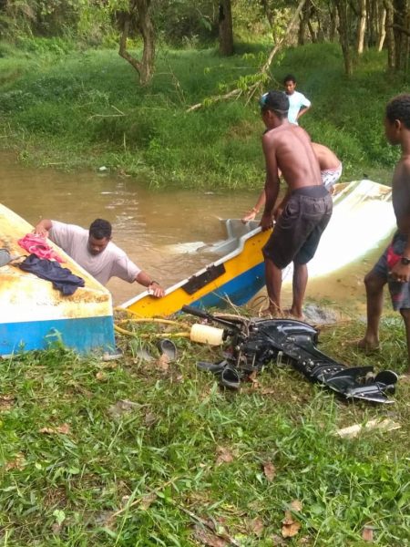 村民正合力打捞被毁坏后沉入河底的船艇。