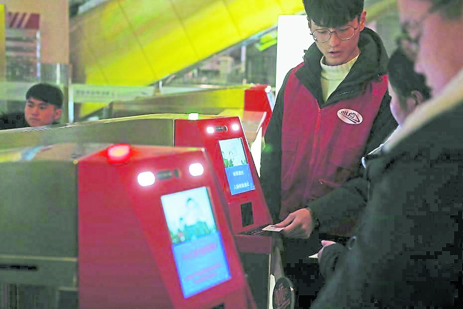 工作人员周一在上海虹桥站协助旅客“刷脸”进站。（中新网）
