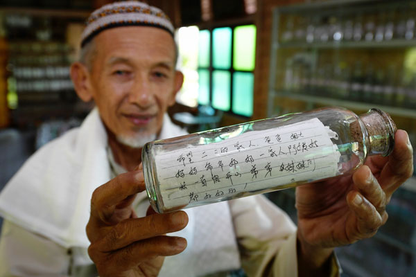 东姑莫哈末阿里展示从海边拾到的中文‘瓶中信’。
