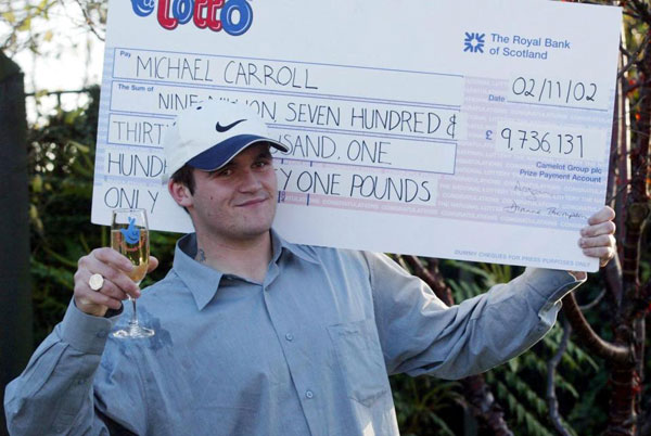 当年19岁的卡罗尔中了970万英镑的彩票奖金，高举模拟支票拍照留念。