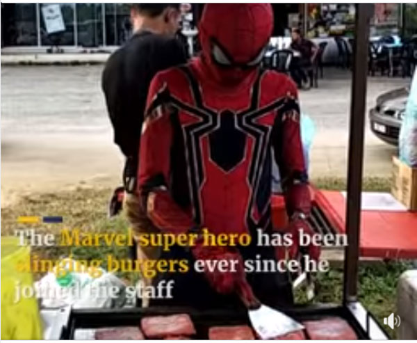 打扮成蜘蛛人在路旁摆档卖汉堡包，深受欢迎。