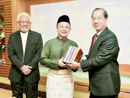 吴恒灿（右起）把马来文版《三国演义》移交给马智礼，并由莫哈末哈达见证。
