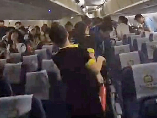 有乘客拍到空姐手持灭火器，在机舱寻找火源的画面。（取自“新加坡眼”）