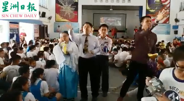 陈长锋（左起）和林思健到访美里某国中时，派糖果给学生的视频引起网民热议。