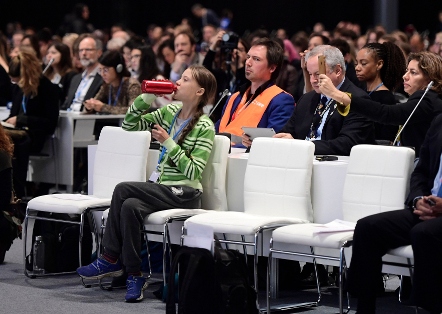 瑞典环保少女桑柏格周三在马德里出席联合国气候变化大会，在台下坐着喝水。（法新社）