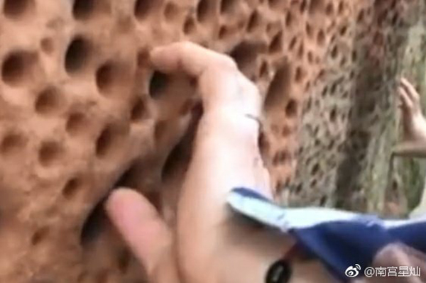 游客把丹霞地貌的红土墙戳出多个小洞。