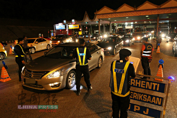 陆路交通局执法人员在收费站设路障，检查往来的道路使用者。
