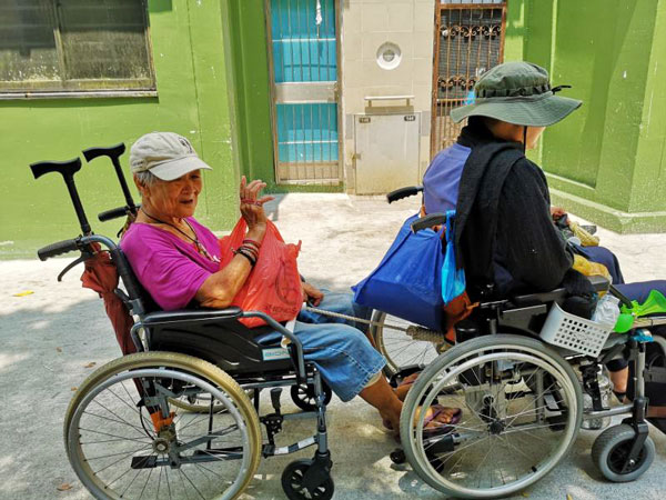 麦志伟在自己和母亲的轮椅之间绑上绳子，每天早上“拉”着母亲到牛车水一座咖啡店。