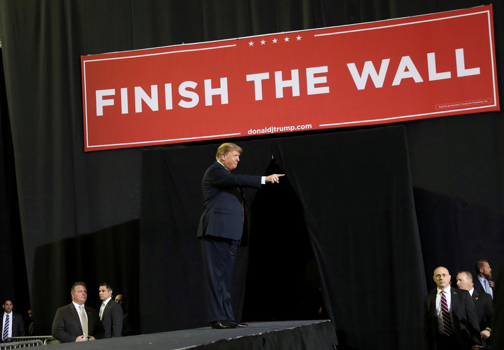 特朗普在今年2月，于德州的竞选活动上，向支持者致意。而台上则高挂着“把墙建完”（Finish the wall）的横幅。（路透社）