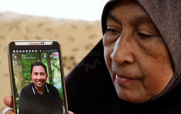 拉希米的母亲罗基雅看着手机内儿子的照片，欣慰儿子逃过一劫。