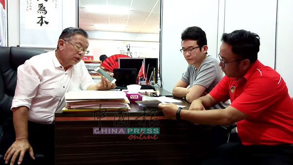 周世扬（左）与向商家募捐资助刊物的非政府组织代表通电话，了解情况，右起是吴勇汉和蔡永兴。