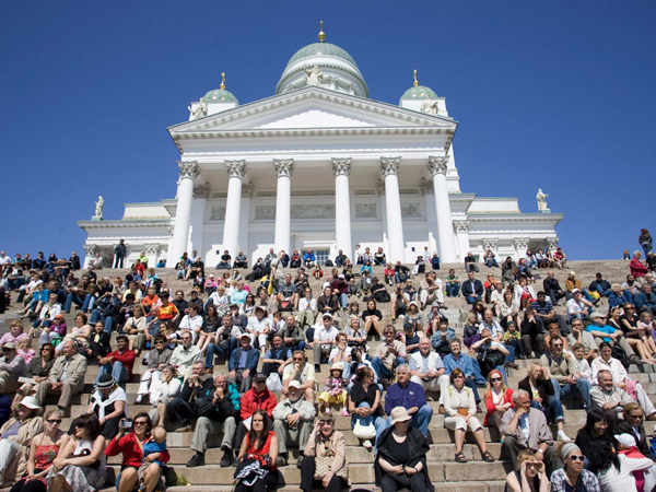 人们坐在芬兰首都赫尔辛基的大教堂前，享受晴天的和暖空气。