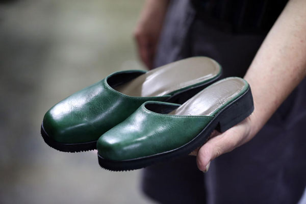 李炯祥展示一双为大小脚顾客制作的鞋子。