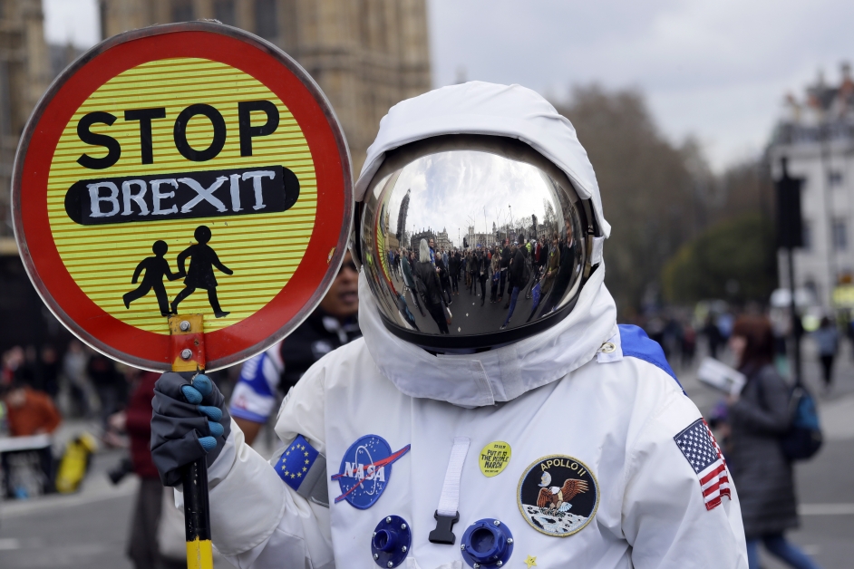 其中1名反脱欧游行参与者一身太空装，手持标语促停止脱欧。（美联社）