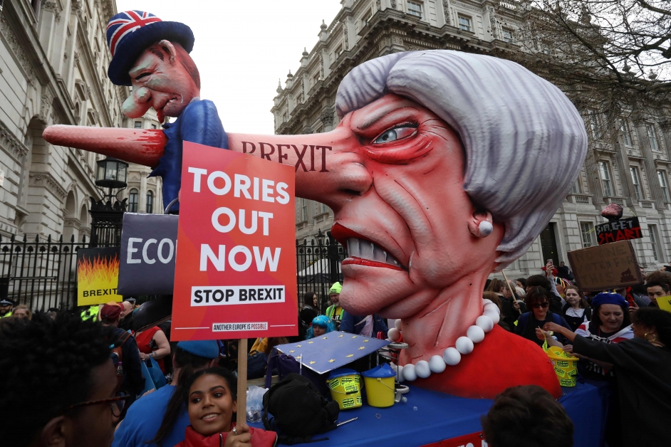游行中出现了英相特丽莎梅人偶，还有超长的尖鼻戳穿了象征英国经济的小人偶，寓意英国脱欧将严重伤害经济。（欧新社）
