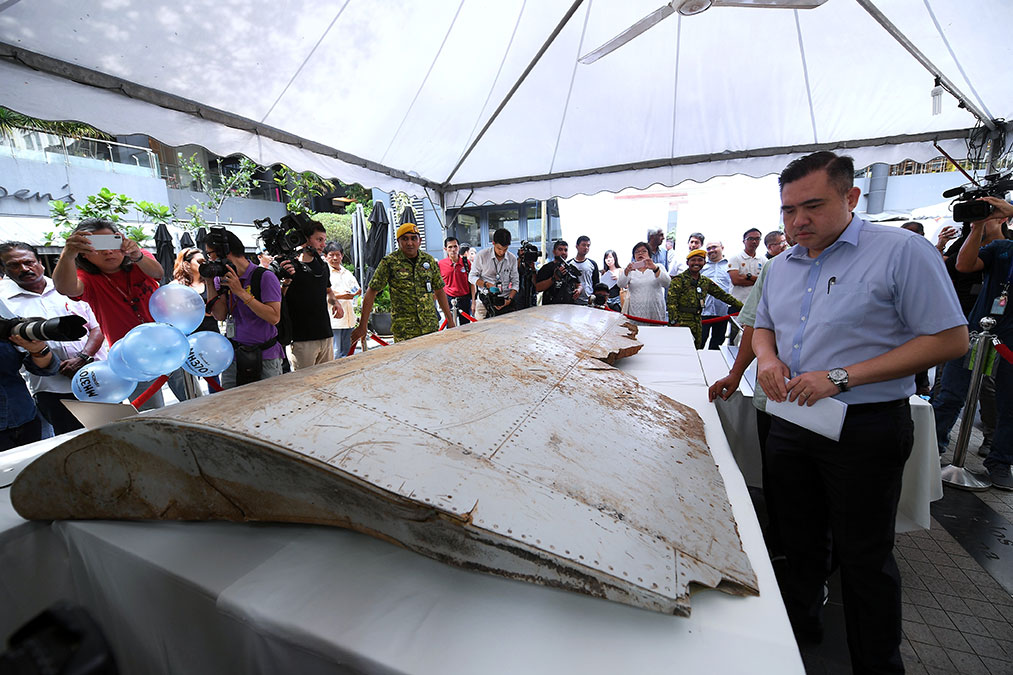 陆兆福（右）在缅怀会上认真观察，来自MH370客机的碎片。
