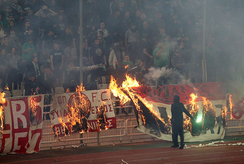 帕纳辛纳科斯球迷焚烧奥林匹亚科斯的横幅。（路透社）