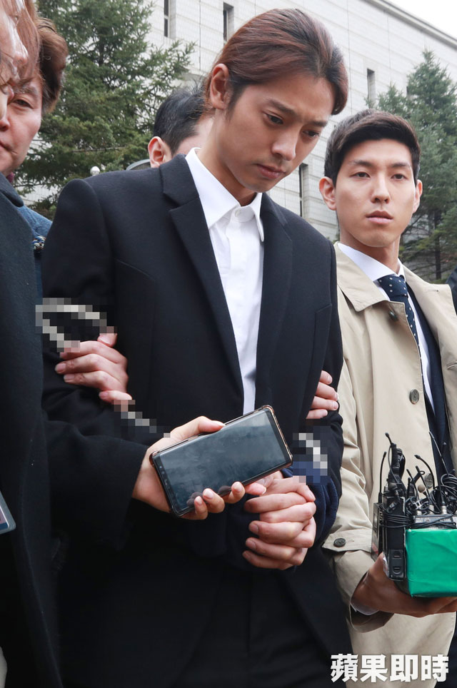 郑俊英双手被绑警绳走出法院，上铐的手特意以蓝布遮掩。韩联社
