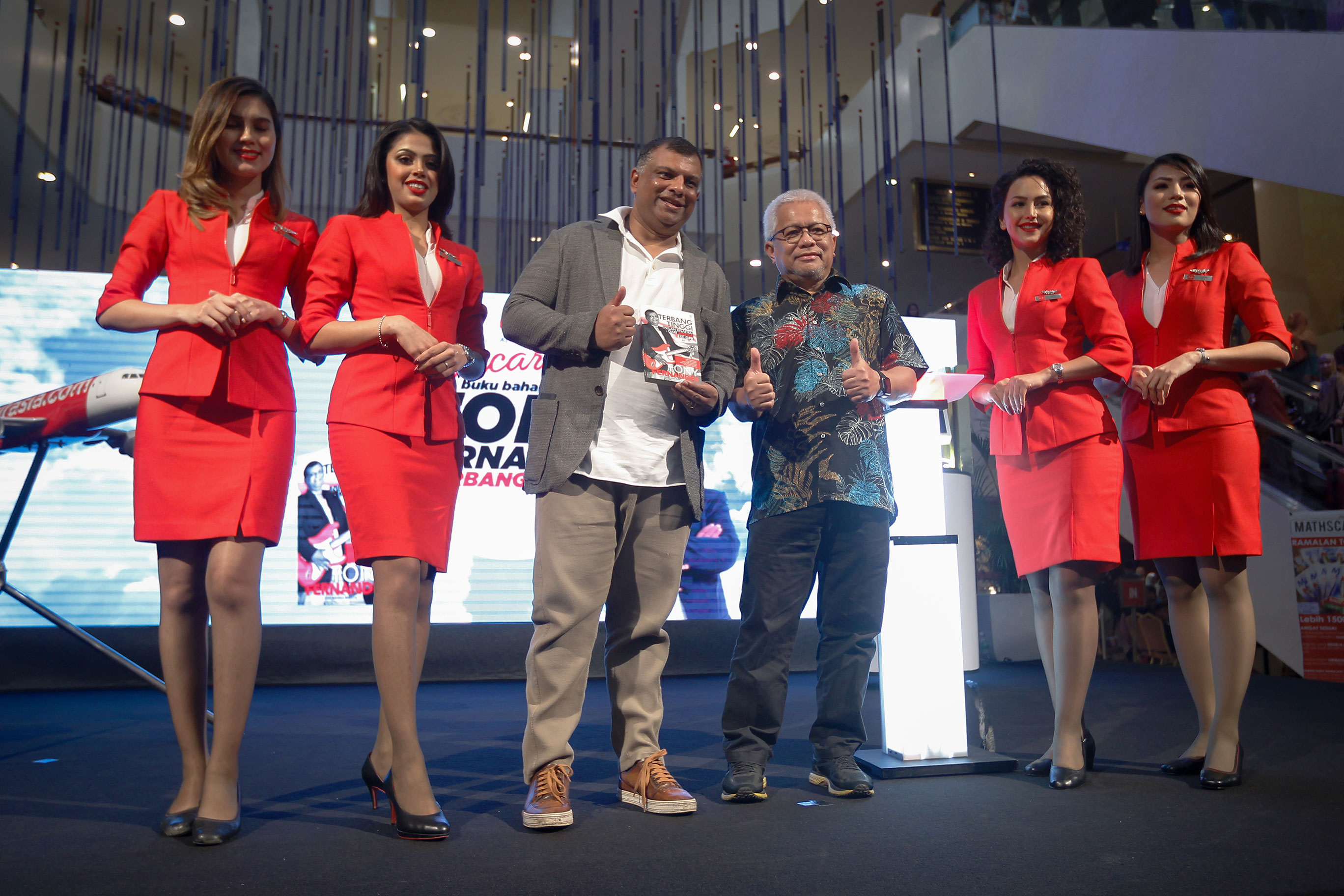 东尼费南德斯（左3起）和胡山慕丁在身穿招牌红色服装的亚航空姐陪同下，推介国文版《展翅高飞》。