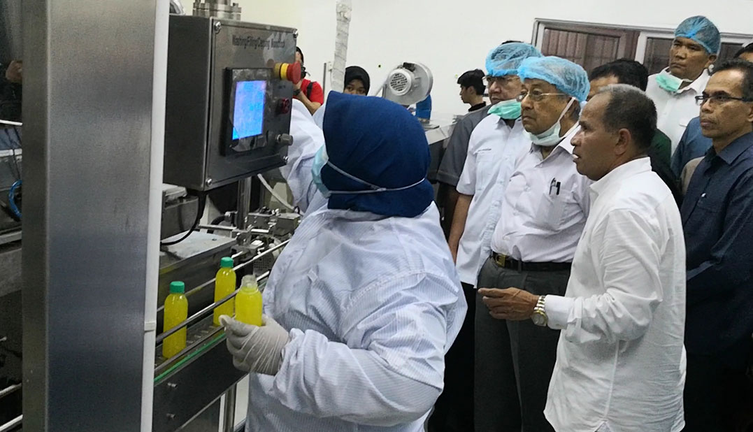 阿武哈山（右起）陪同马哈迪，参观黄梨汁制作过程。