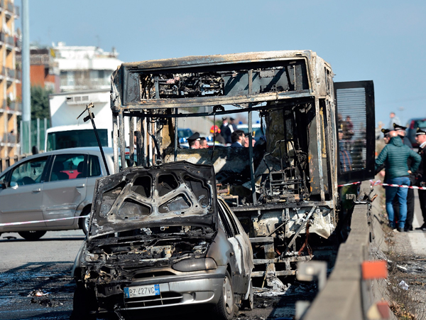 校车遭纵火后烧到仅剩下骨架，前面被撞的一辆小轿车也被烧毁。