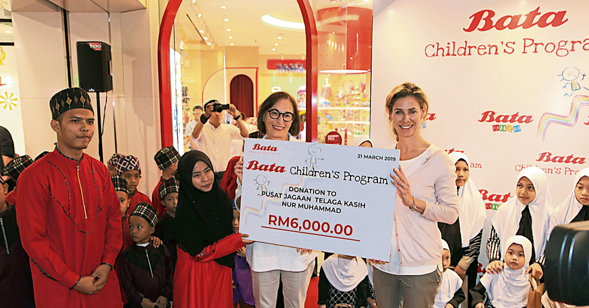 蜜儿詹（右起）与克丽斯汀施密特一起移交6000令吉模拟支票予Pusat Jagaan Telaga Kasih Nur Muhammad儿童之家负责人。