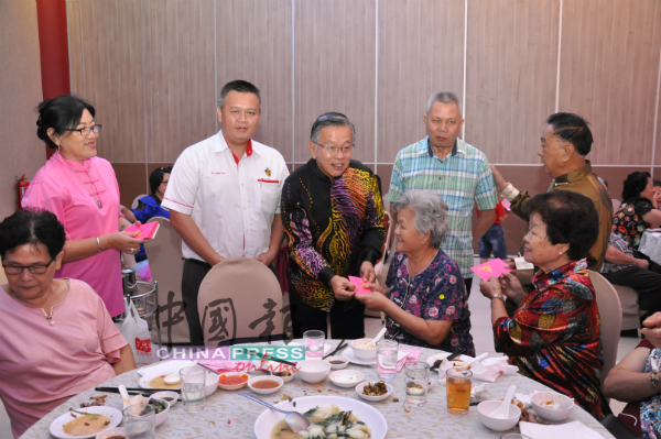 　周世扬（中）与议员吴金财（左2起）和叶耀荣，一起在孝亲敬老环节，沿桌分发红包给年长者。