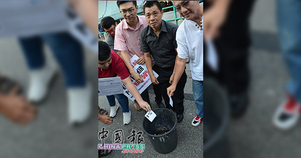 高举大字报后，胡伟豪（左2起）、李祖维把1%的字条丢进垃圾桶内。