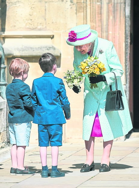 周日在温莎堡圣乔治教堂外，两名小男为女王献上花束。（路透社）
