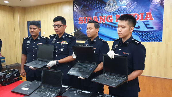 鲁迪（左2）与建功警官展示警方起获的手提电脑。