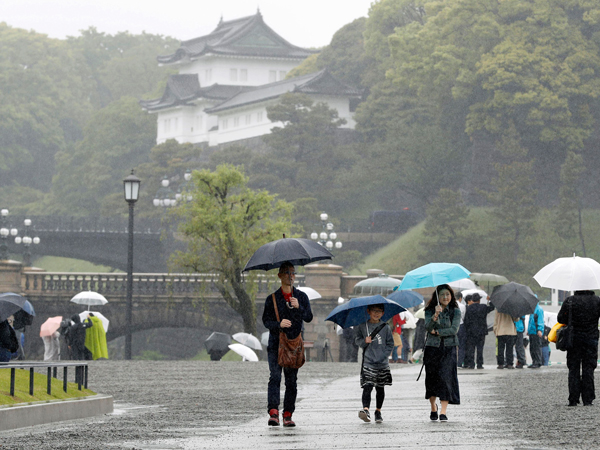 日本民众周二一早冒雨到皇宫附近。（美联社）