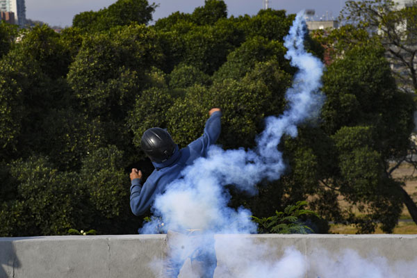 一名反对派示威者，向一处仍支持马杜罗管治的军事基地，抛掷催泪弹。