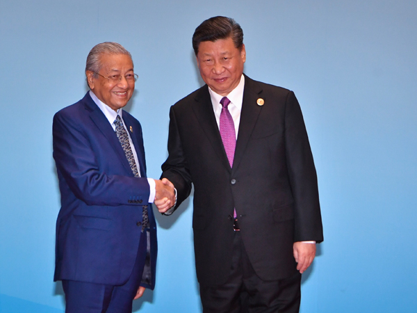 马哈迪（左）在出席圆桌会议时，与习近平握手。