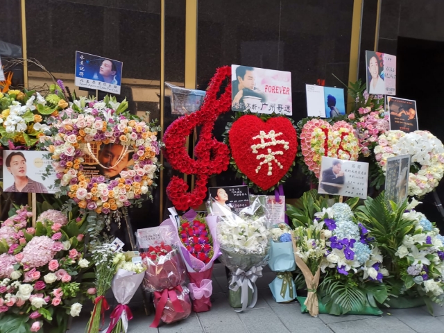 “哥”迷带着鲜花、花牌、照片等到文华酒店门外悼念哥哥。