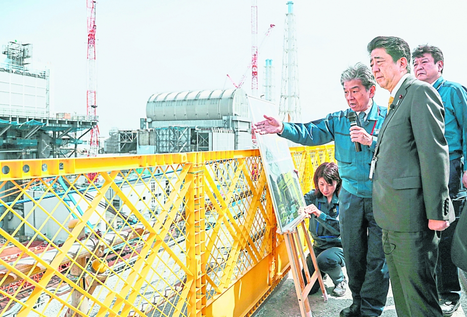 日本首相安倍晋三（前右）周日仅穿一身西装，视察福岛核电厂与周边作业。（美联社）