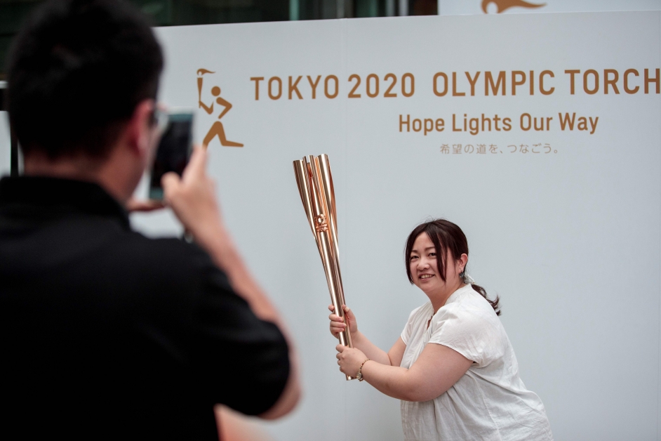 日本女子手持东京奥运会火炬拍照。（法新社）
