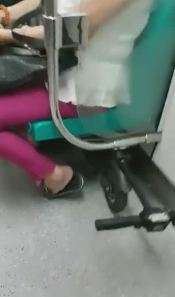 洋汉将折叠好的电动踏板车塞进列车座位底下。（受访者提供）