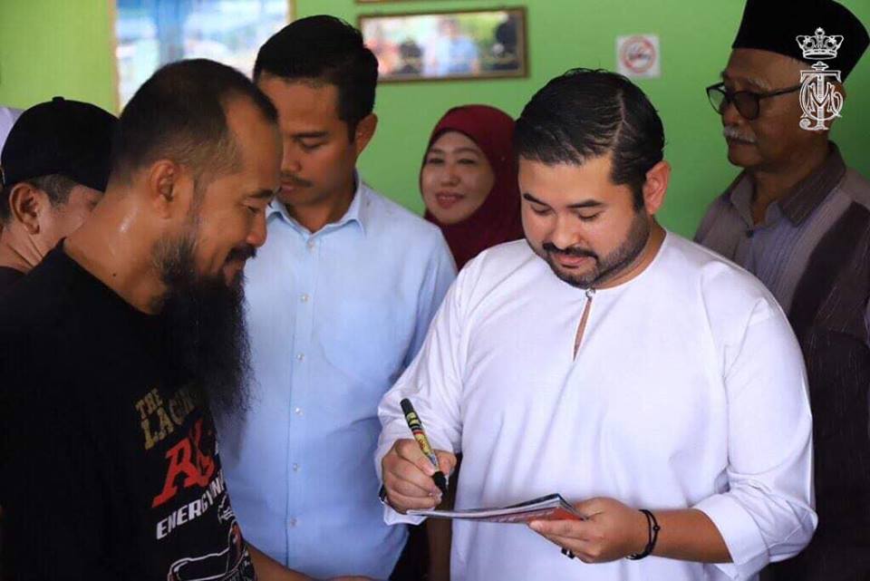 巴罗永平路4英里马来甘榜的村民向柔佛王储东姑依斯迈（右）索取签名。
