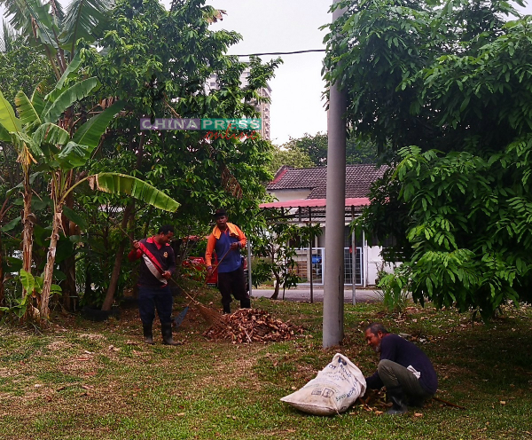 清洁工友在游乐场清理树叶。